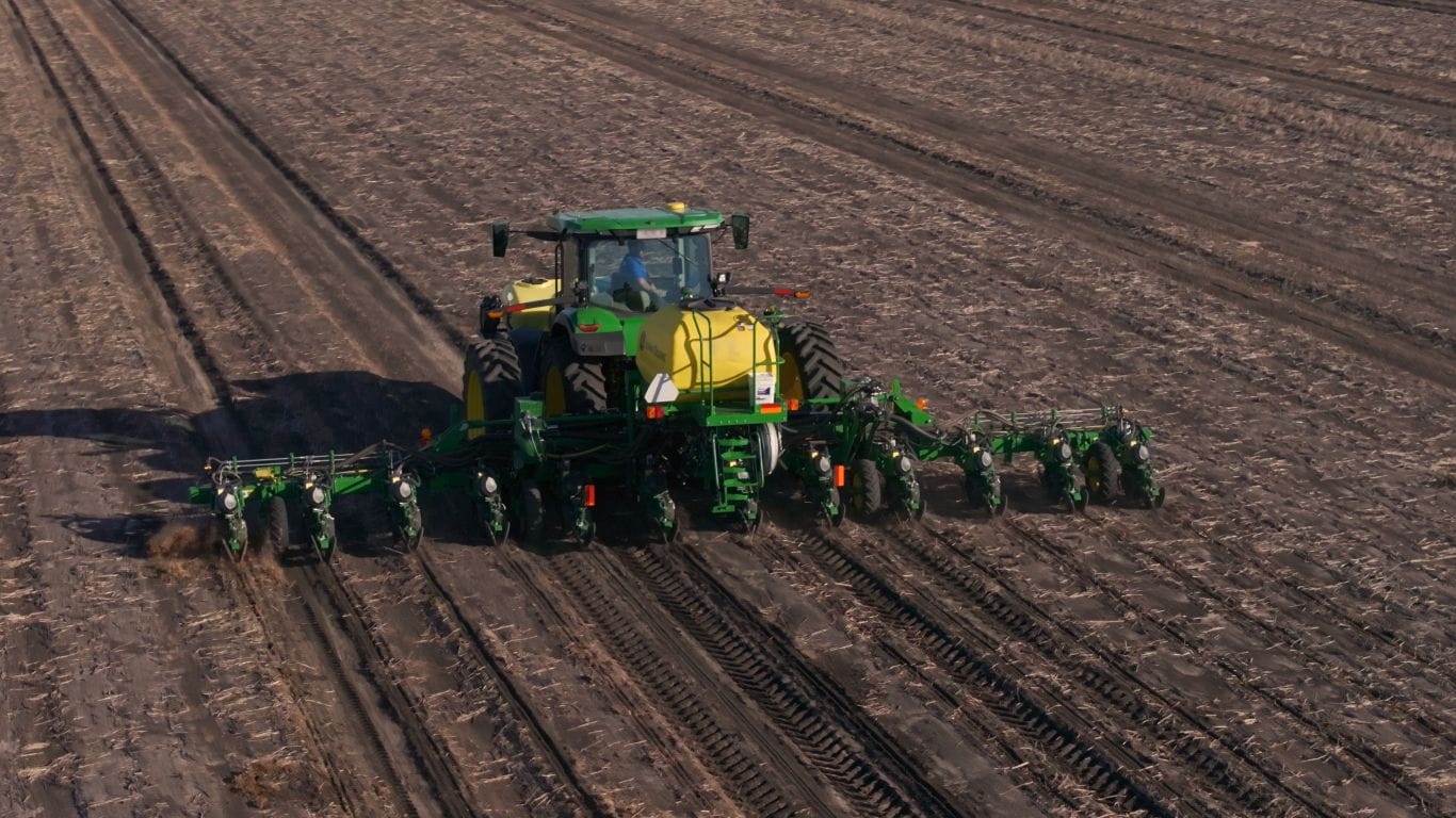 Green and yellow machine planting in paddock.