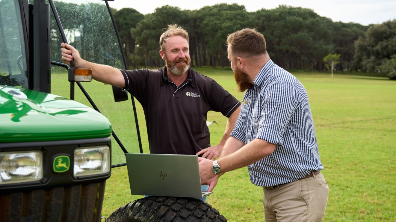Two men talking beside John Deere 5075E.