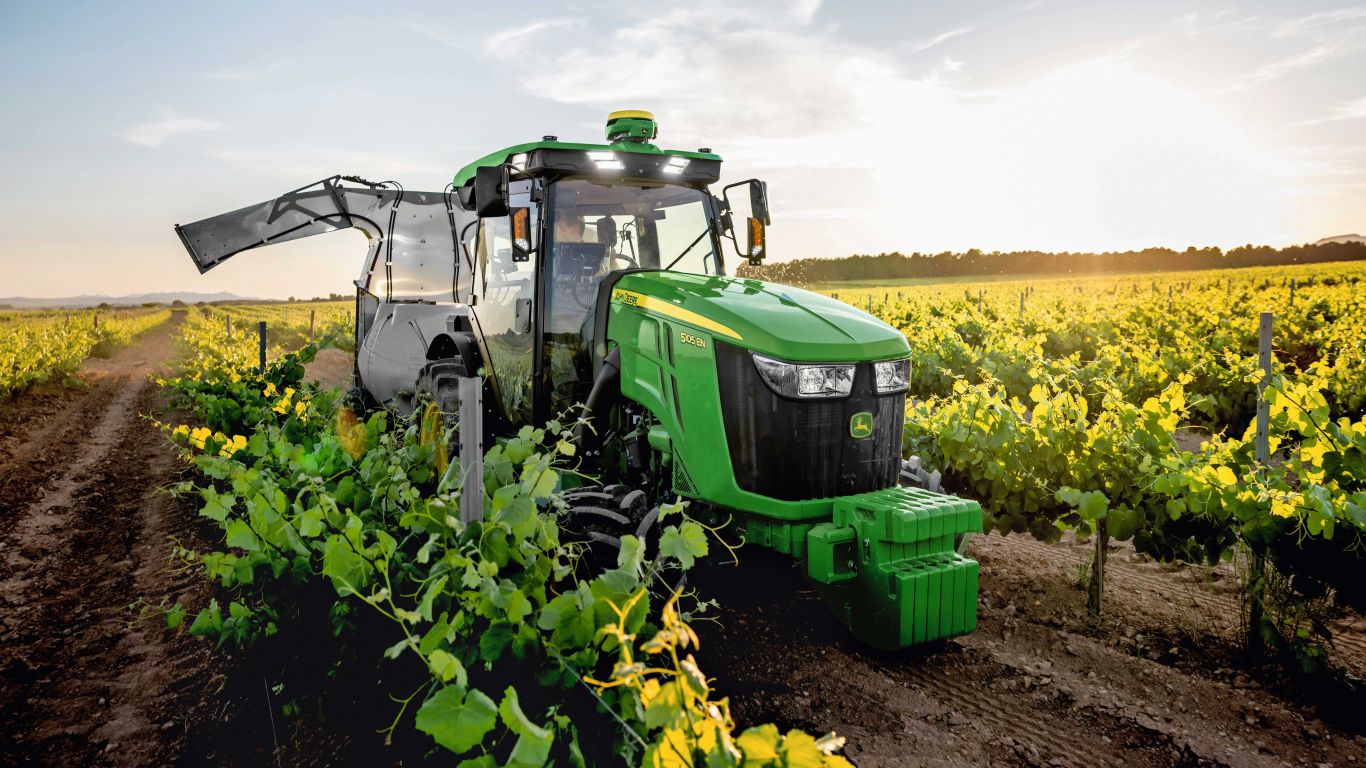 Green and yellow John Deere tractor in between vines