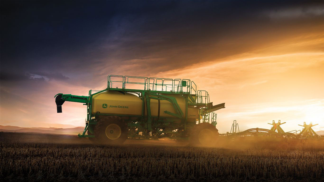 Large green and yellow machine with black and yellow wheels in paddock at dusk