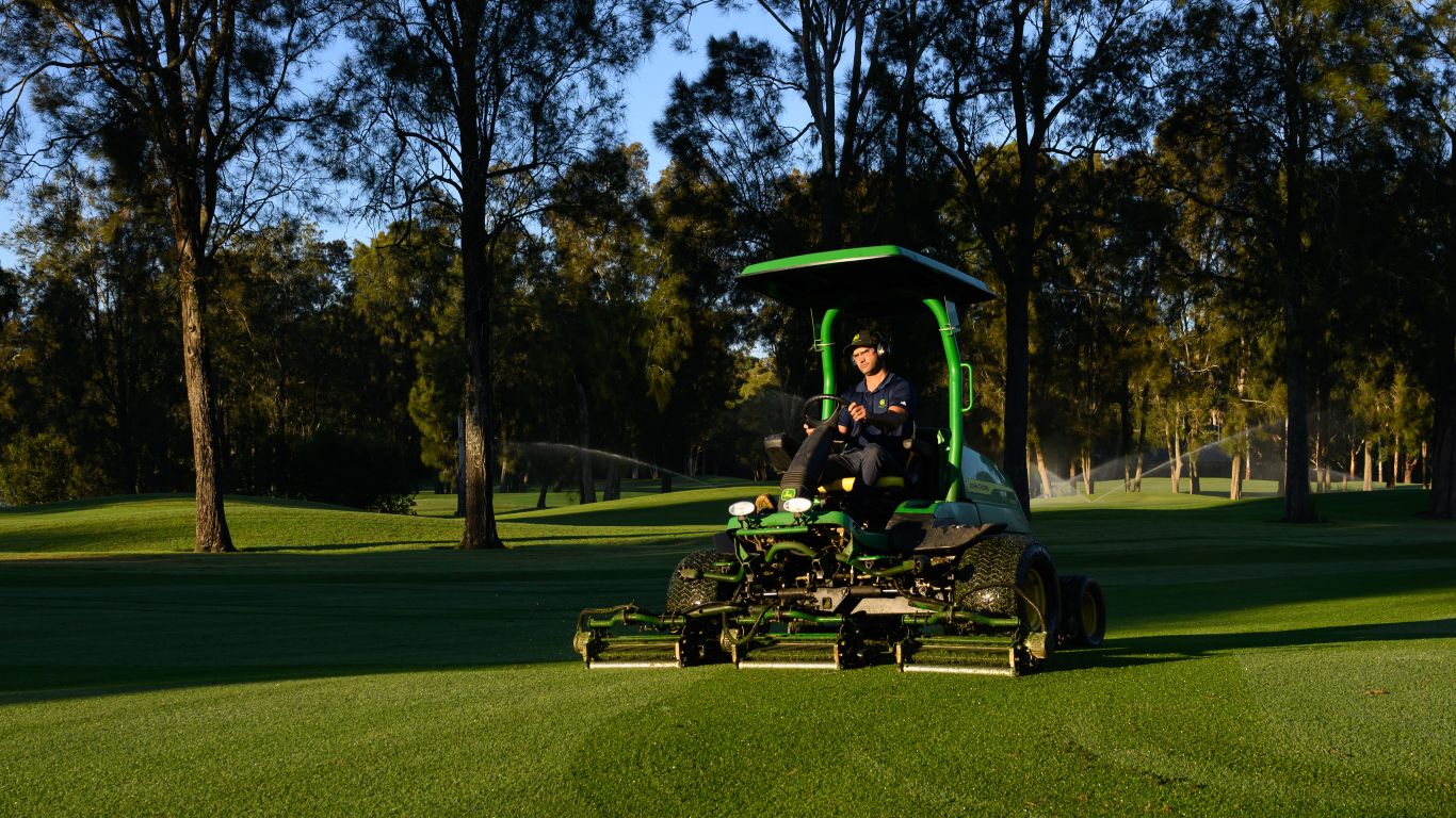 A man is driving a John Deere 2750 PrecisionCut Triplex Mower.