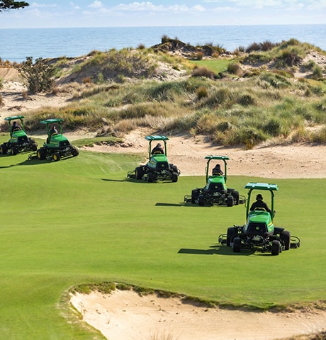 Several lawn mowers tending a golf course