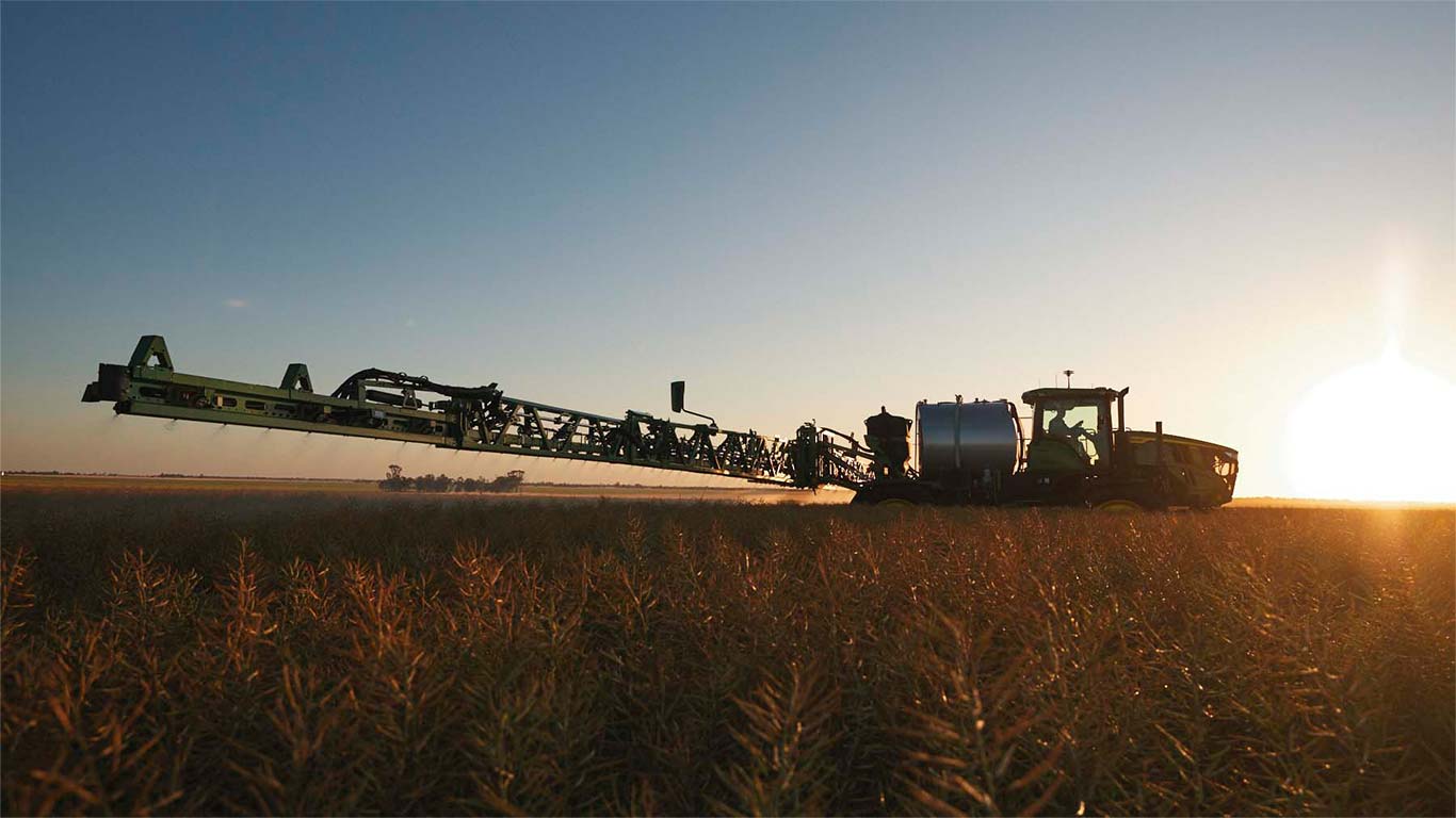 John Deere sprayer in paddock and sunset.