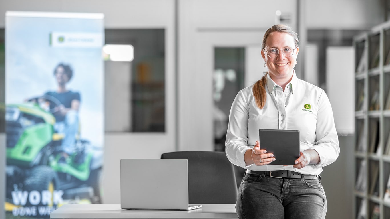 a female employee smiling in an office with a tablet