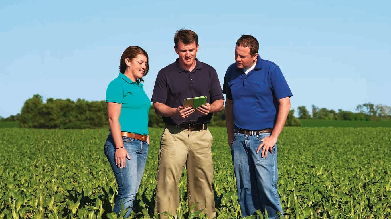 a group of people looking a tablet in a field