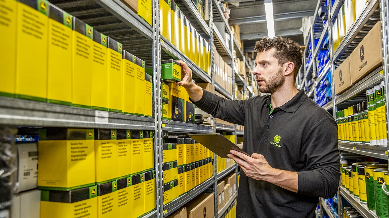 a man in a backroom looking at parts boxes and holding a clipboard