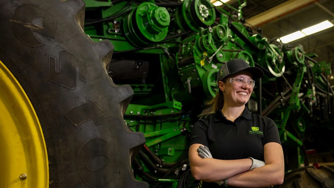 Smiling women technician in front of harvester parts