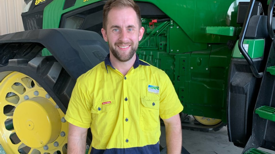 Josh Carter smiling in front of a tractor