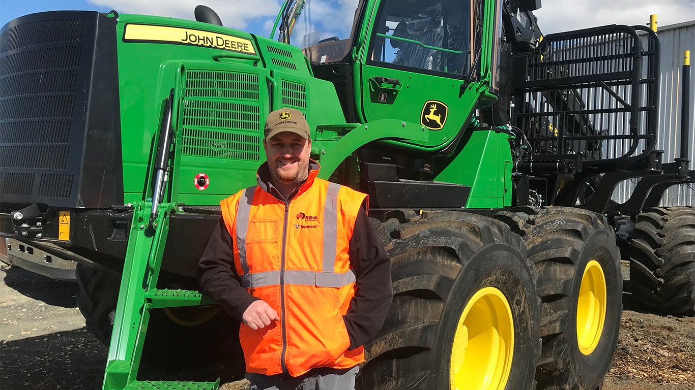 Troy McMahon smiling in front of a tractor