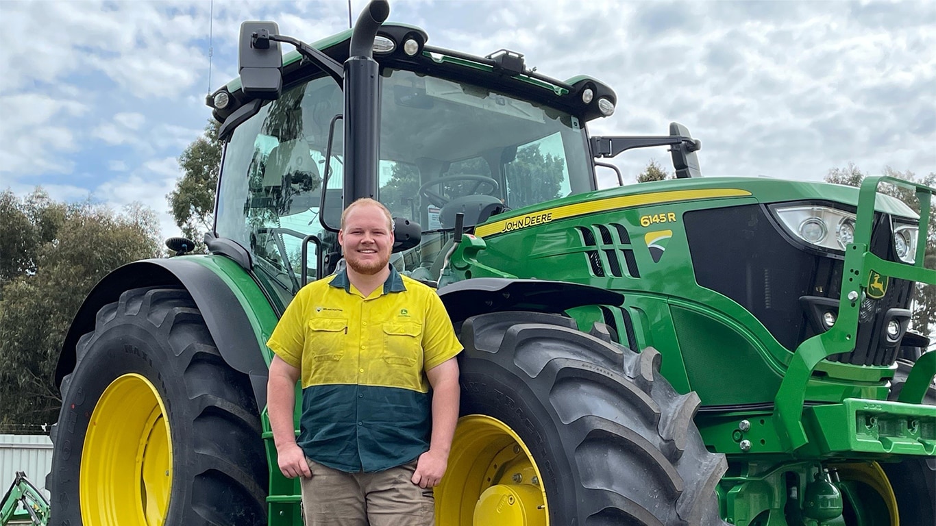 Caleb Dover smiling next to a tractor