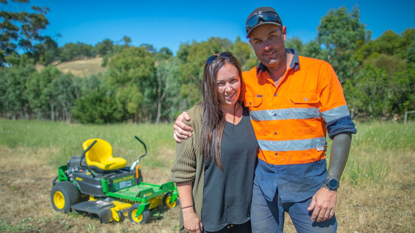 Husband and wife standing by Ztrak mower