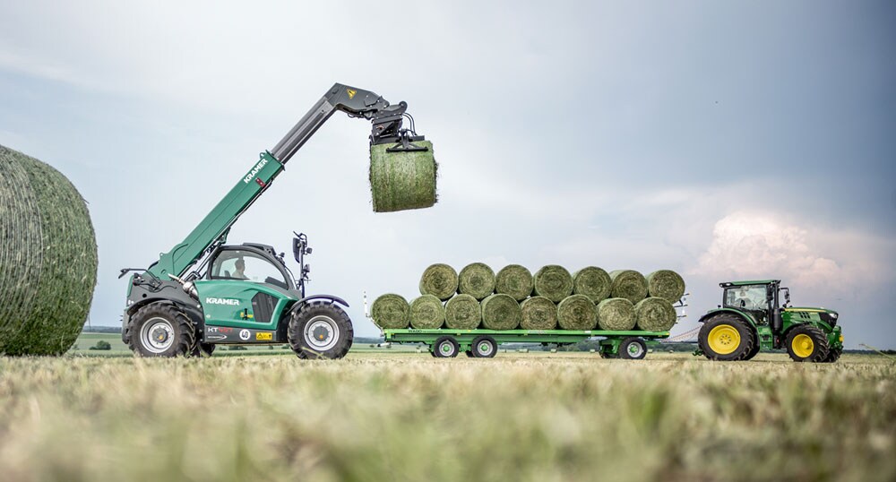 John Deere and Kramer agriculture equipment moving hay bales