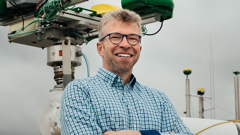 Georg Kormann standing by a robotic arm.