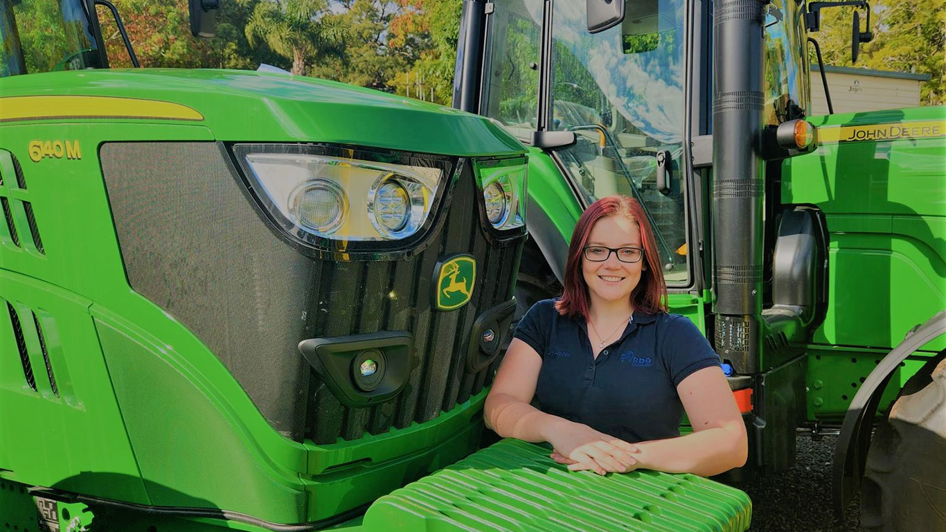Kaylyn-Rose Netrval in front of John Deere equipment