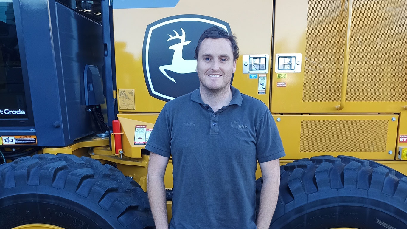 James Andrew in front of John Deere equipment