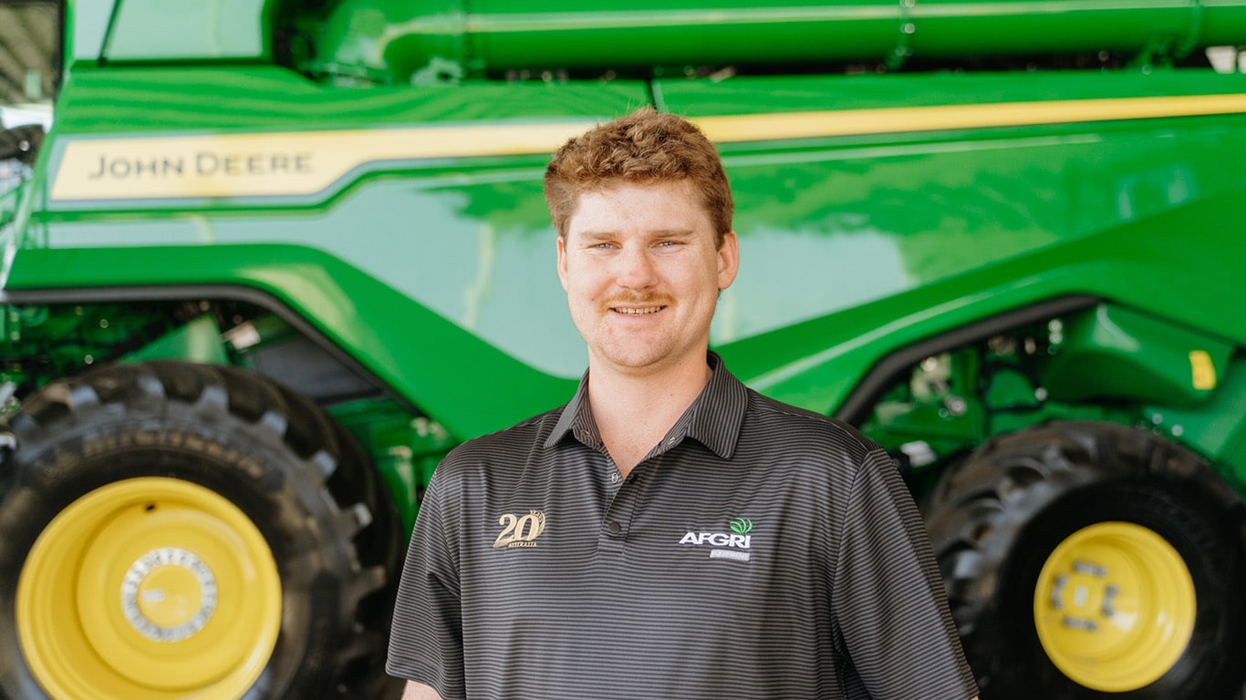 Bradley Skinner standing in front of agriculture equipment, smiling at the camera.