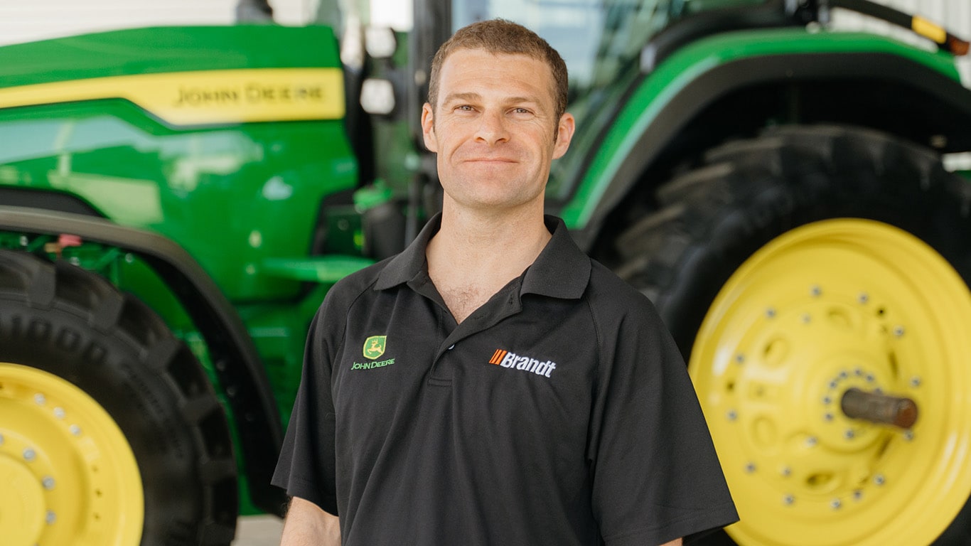 Marcus Vine standing in front of a tractor, smiling at the camera.