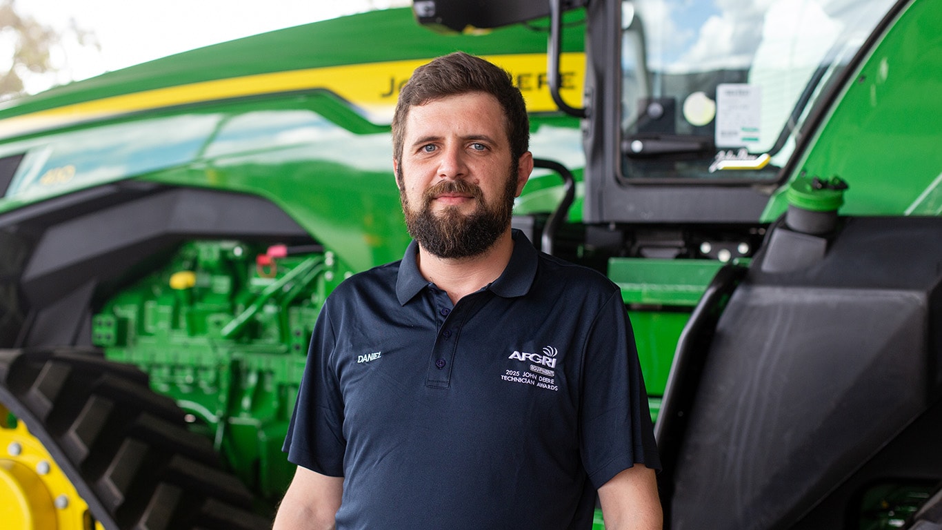 Daniel standing with his arms crossed in front of 9R 540 Tractor
