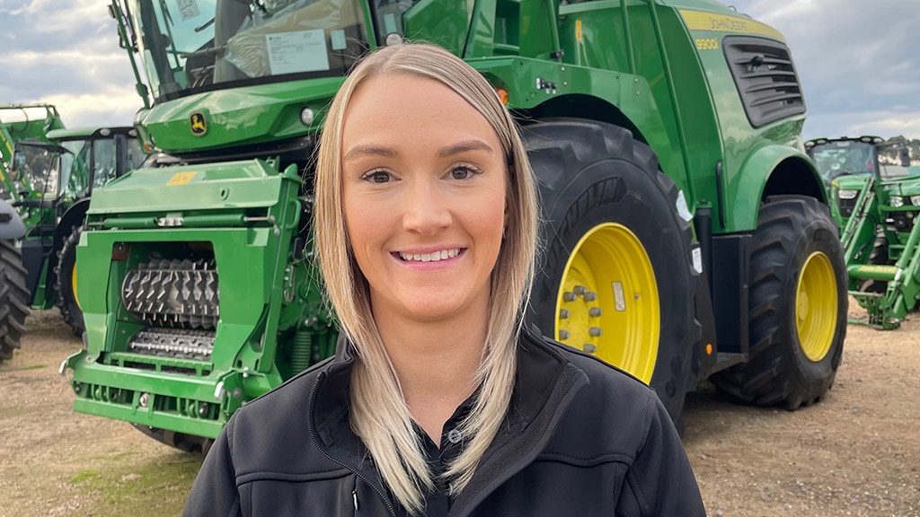 Sarah smiling in front of 9900 self-propelled forage harvester