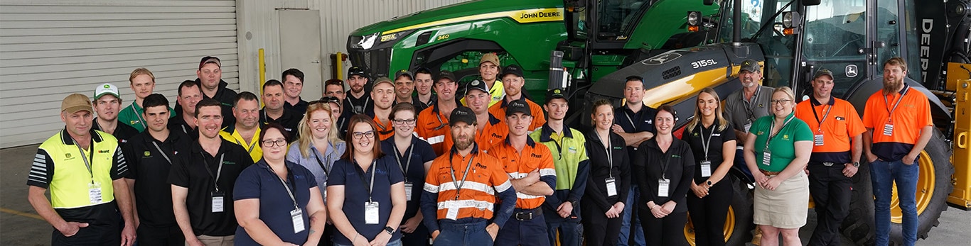 Tech awards winners grouped in front of Deere equipment