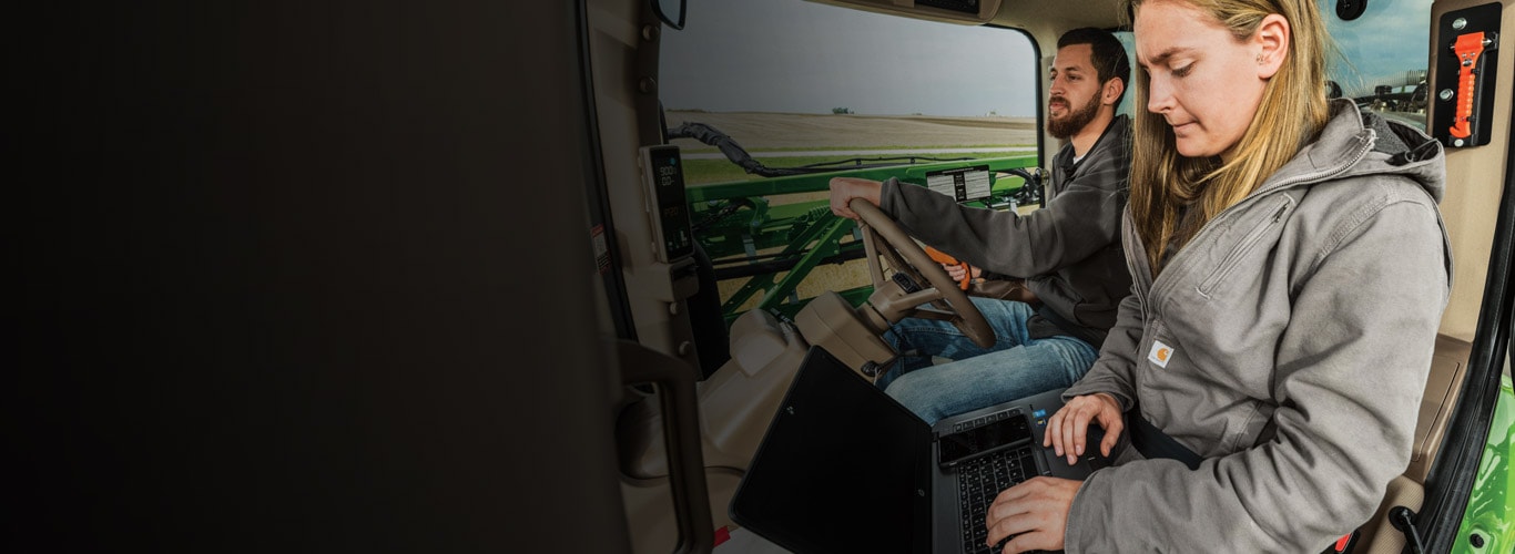 A man and a woman in a tractor cab using Customer Service ADVISOR while on the job.