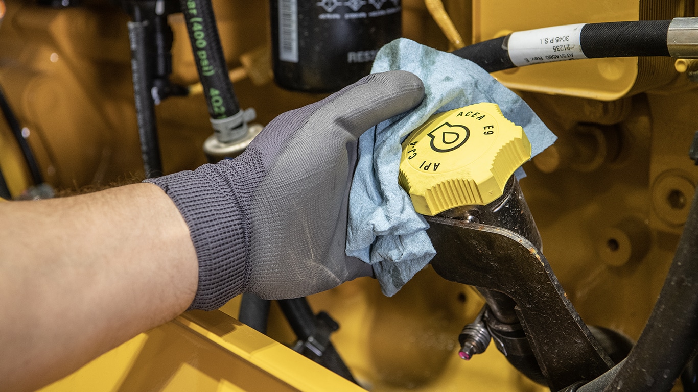 Gloved hand holding a towel turning an oil cap