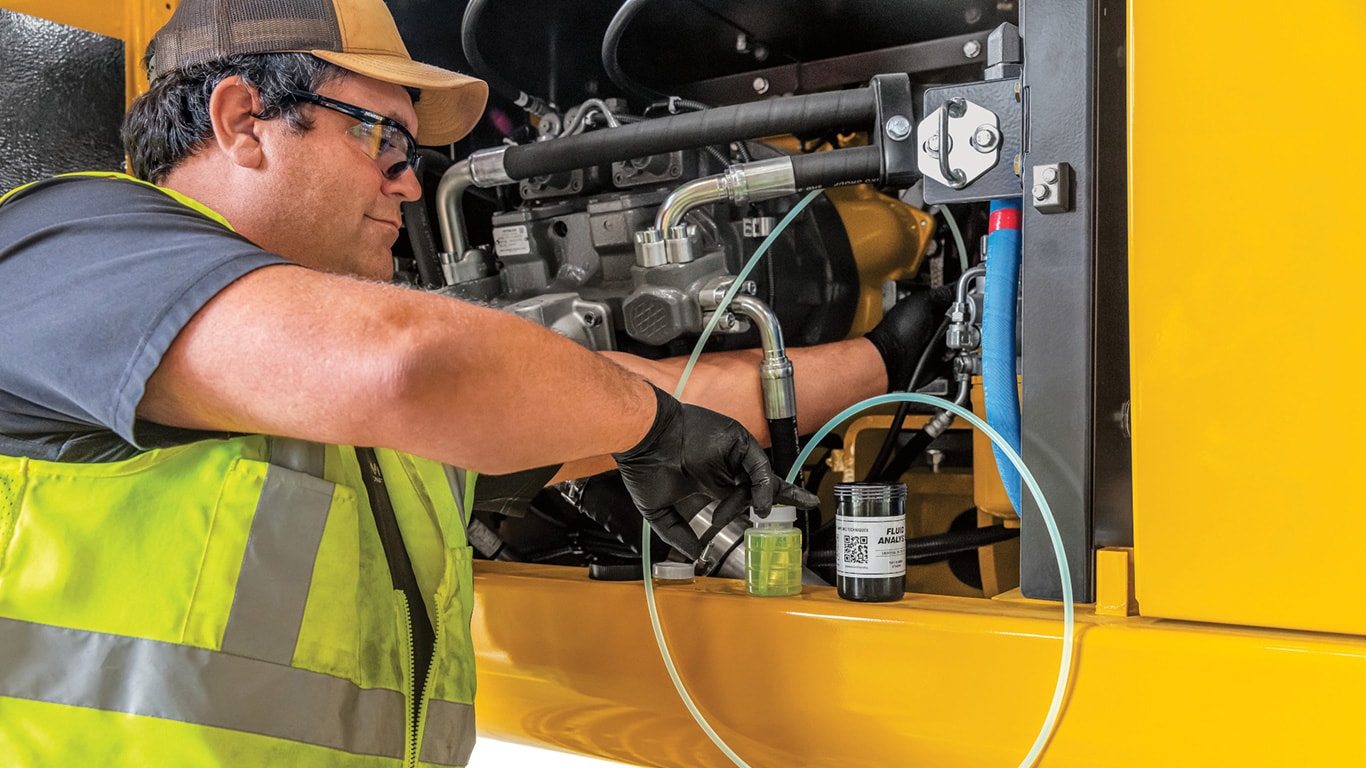 A technician reaches into the engine bay with special tubing and equipment to extract a sample of oil.  The small oil sample bottles are now ready to be sent to the laboratory for testing.