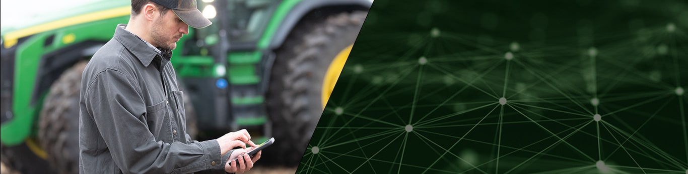 Photo of a farmer using his smartphone to start the John Deere Autonomous 8R Tractor.