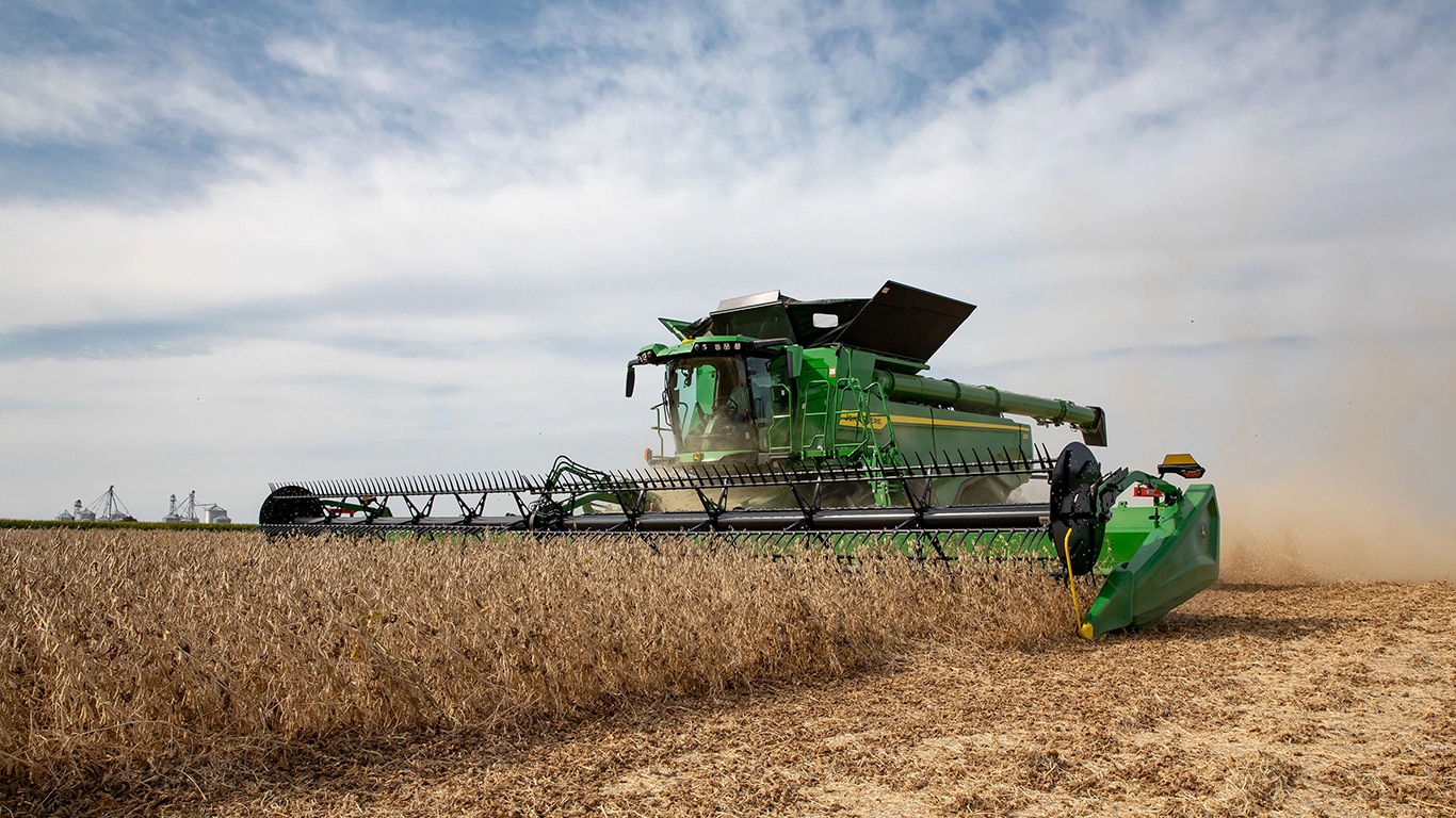 A John Deere X9 Series combine in a field of soy.