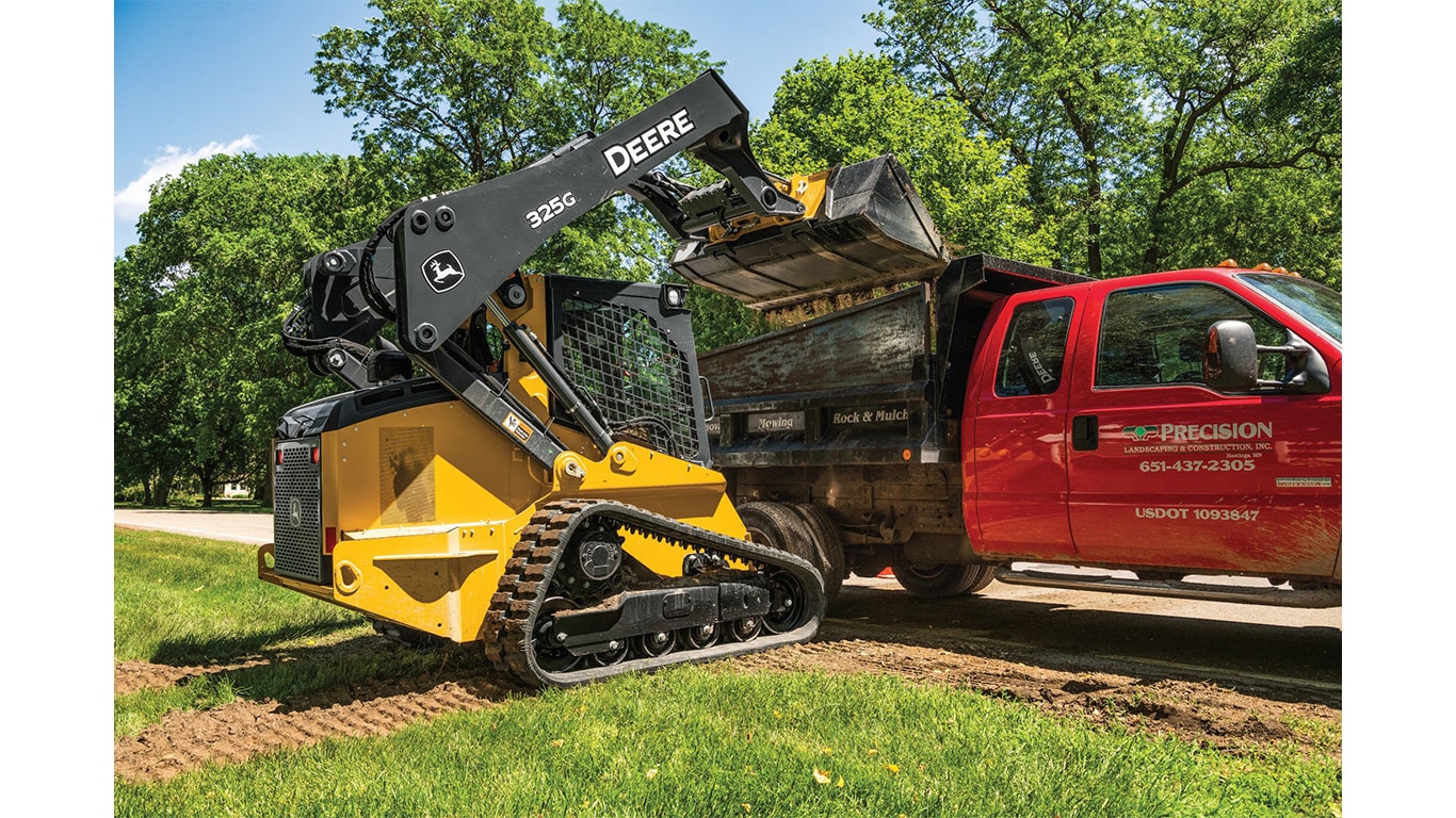 A 325G Compact Track Loader dumping materials into a dump truck.