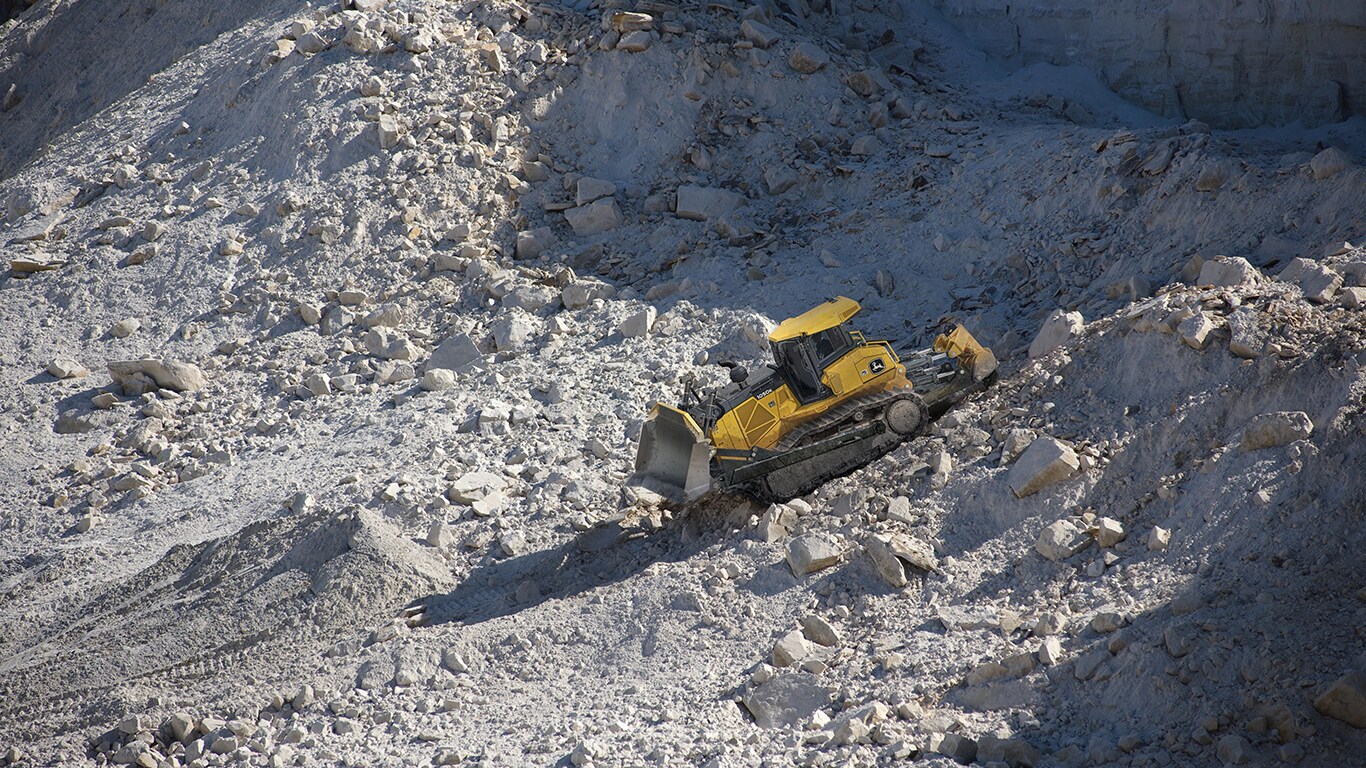 A 1050K Dozer pushing rock at a quarry worksite.