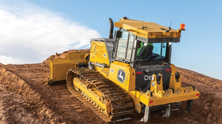 700L Dozer pushing dirt up a hill on unlevel terrain.