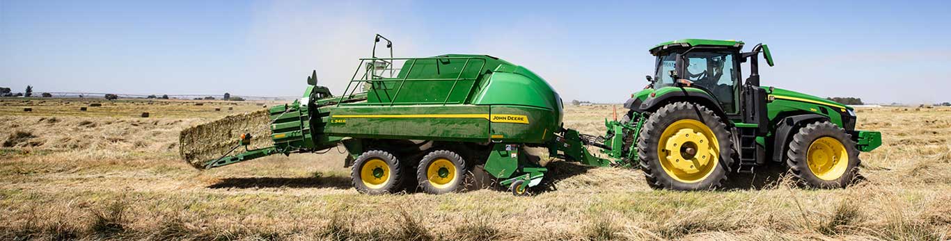 John Deere tractor attached with L341R baler carrying large bale