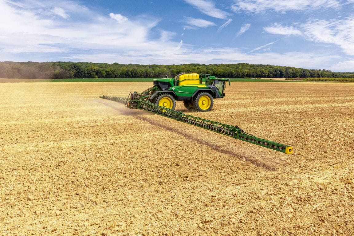 John Deere 500R self‑propelled sprayer applying crop protection across a harvested field with an extended boom.