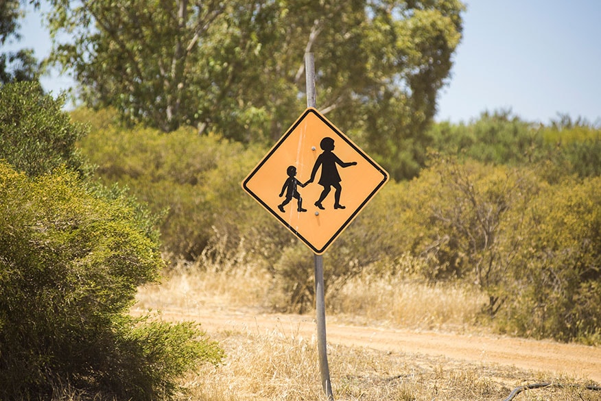 Children crossing sign near a sandy road