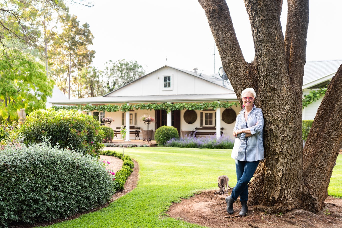 Julie Armstrong smiling underneath tree near garden