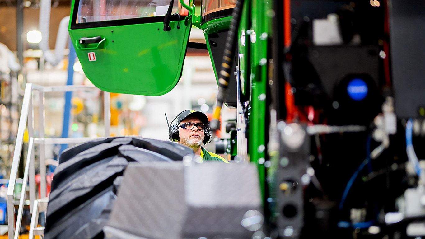 Forest machine with an open door and a man behind the tyre