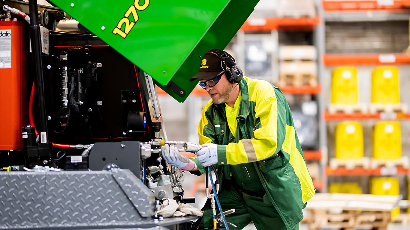 A man is installing a hose to a forest machine