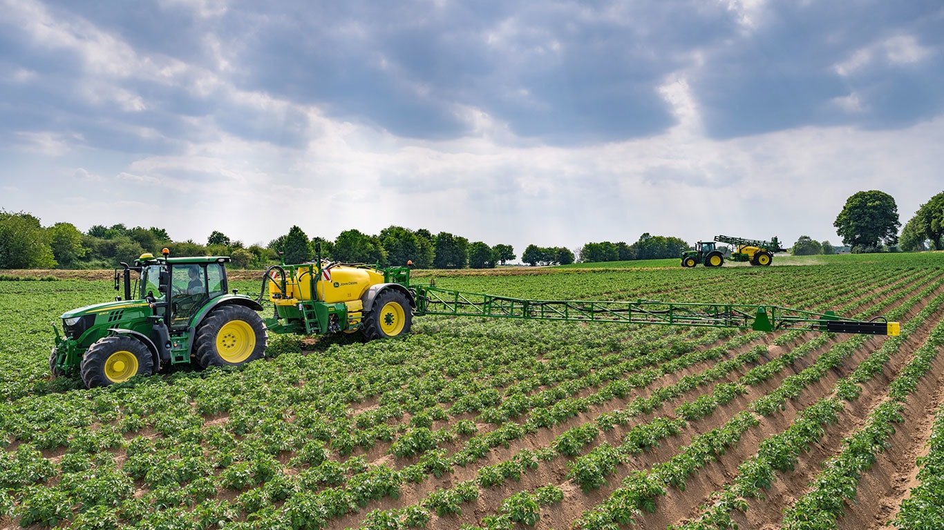 tractor pulling a sprayer in a field of crops