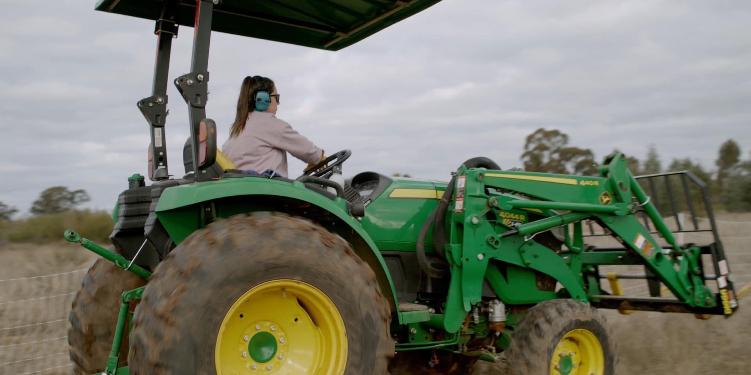 Emma driving a John Deere utility tractor