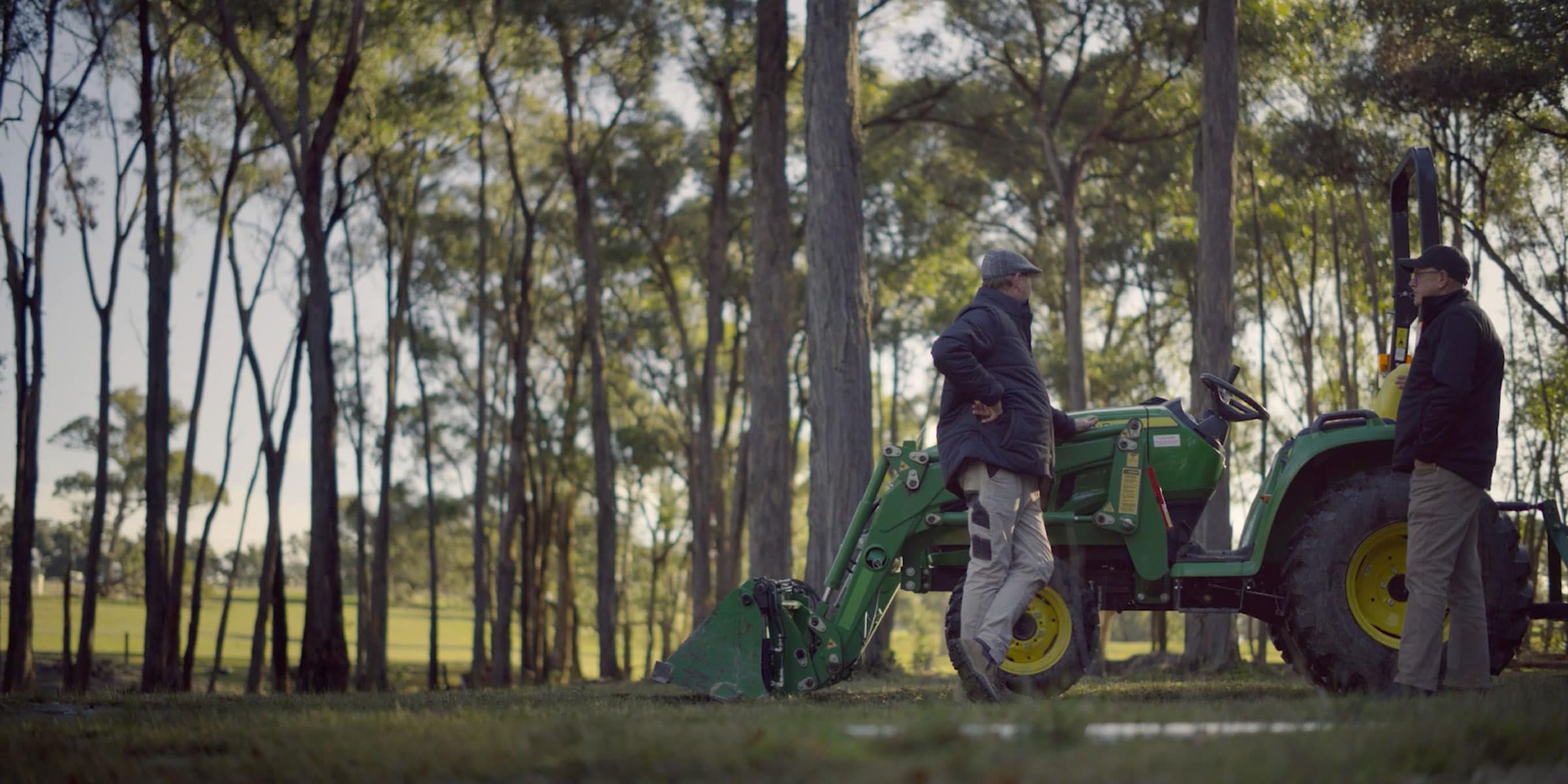 David Brooks and his John Deere Dealer leaning against a John Deere utility tractor
