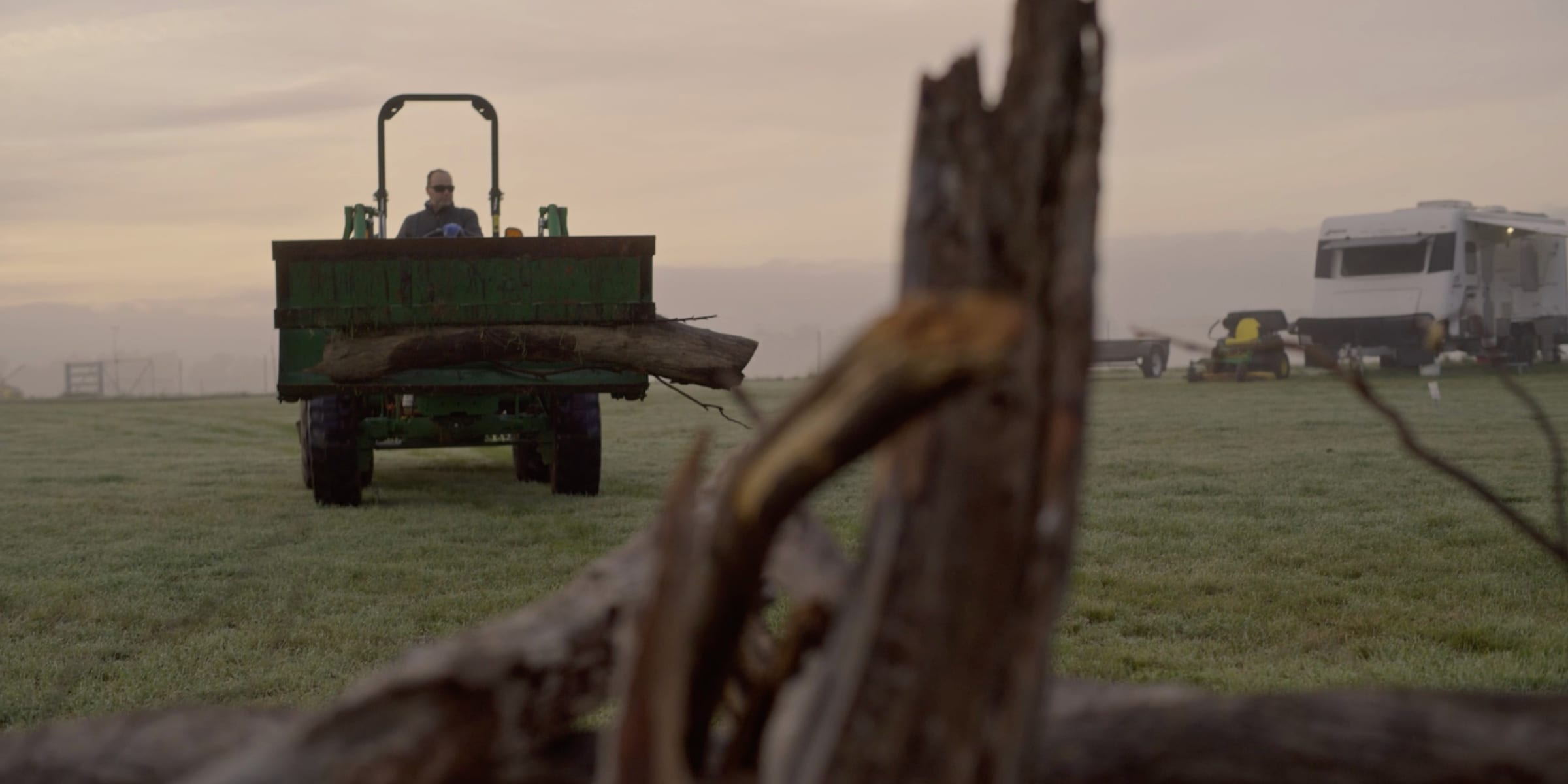 Front view of a man driving a John Deere utility tractor