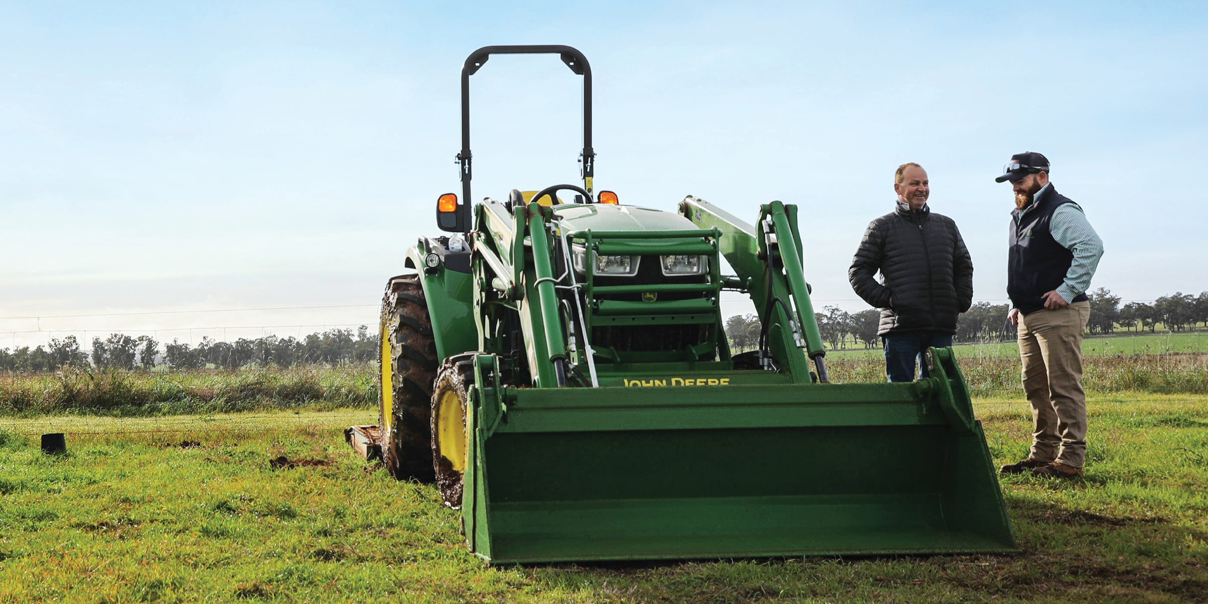 Fred Furner and a John Deere Dealer standing next to a John Deere utility tractor