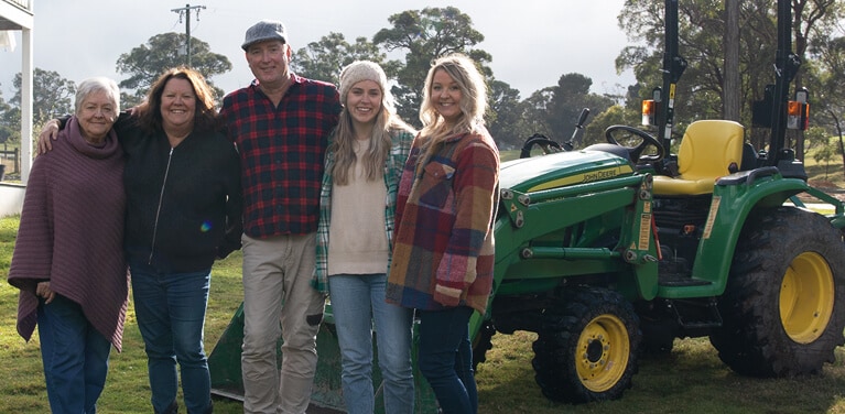 A portrait of the Brooks family in front of their utility tractor