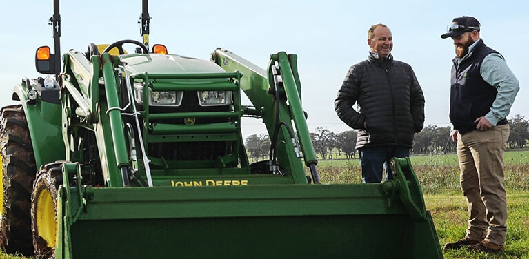 Fred Furner and a John Deere Dealer standing next to a John Deere utility tractor