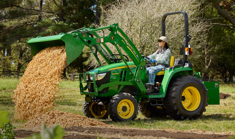 woman gardening with a Deere compact tractor in the background