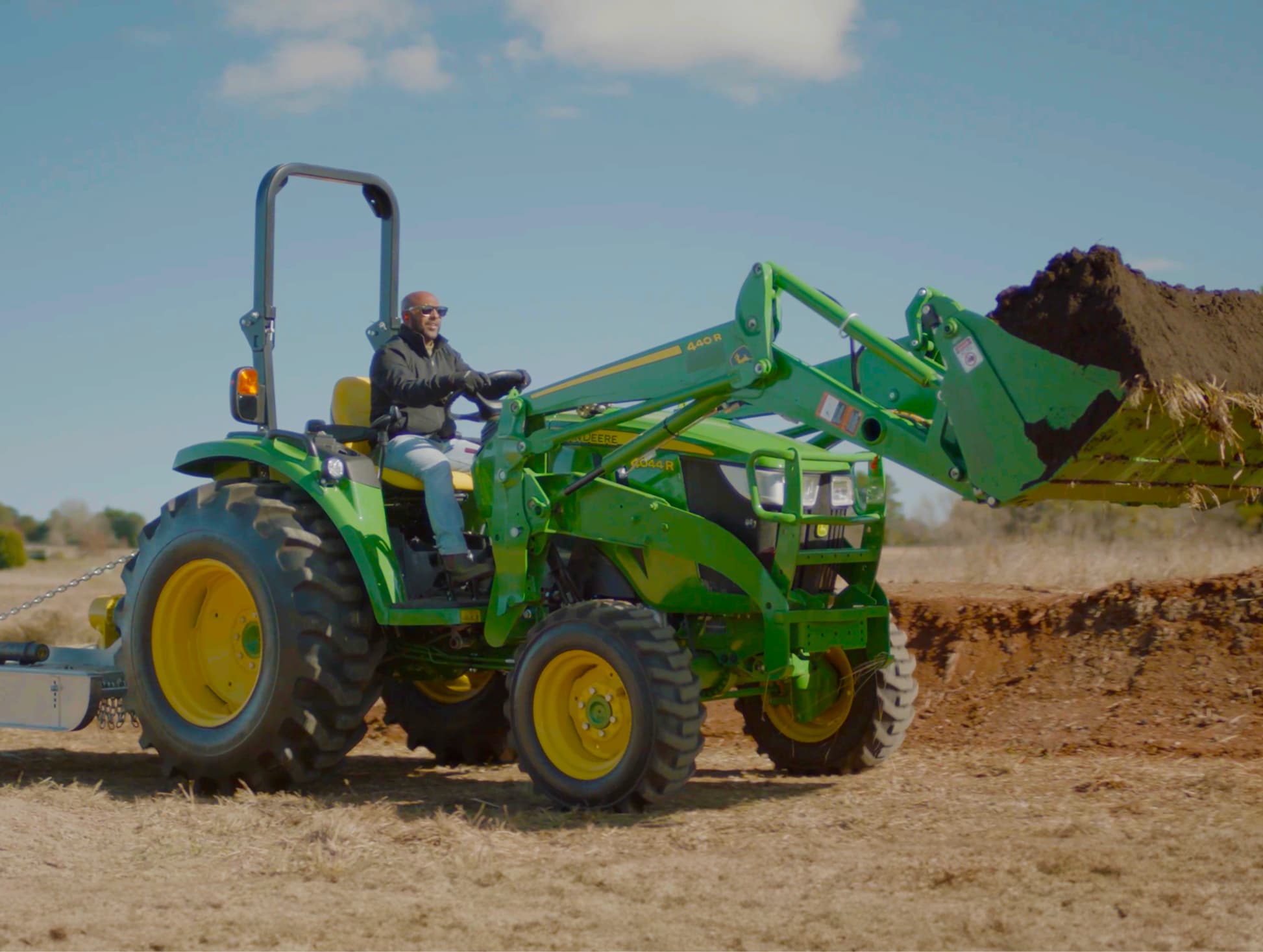 Man creating a backyard dirt bike track with his John Deere Lifestyle tractor.