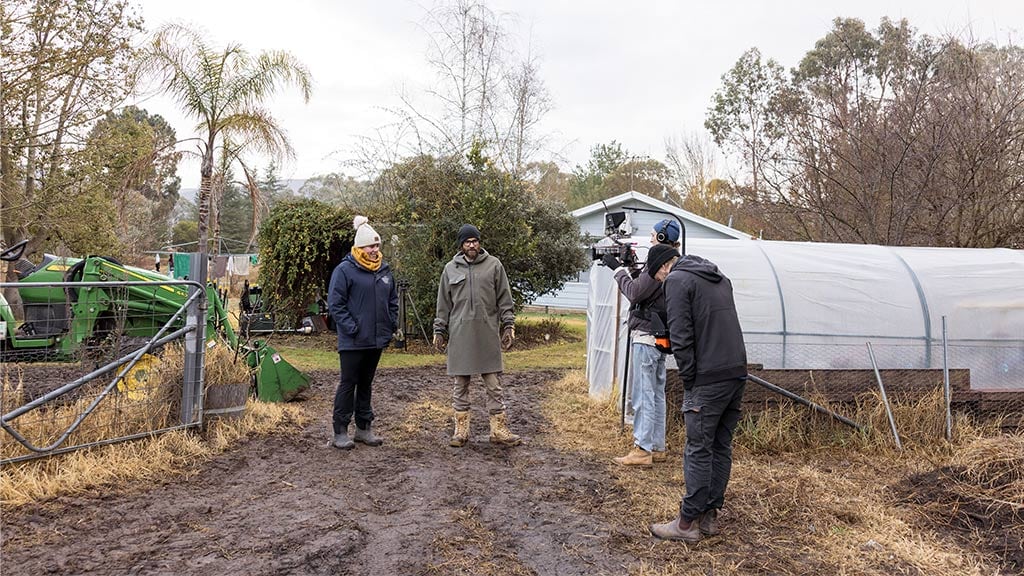 Two people outdoors smiling, one holding a long piece of paper.