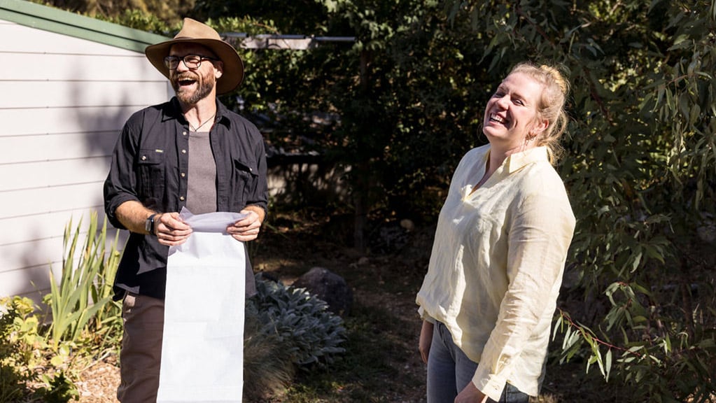 Small bird with yellow belly and gray head on branch in dense, leafless thicket.