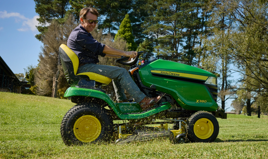 woman gardening with a Deere compact tractor in the background